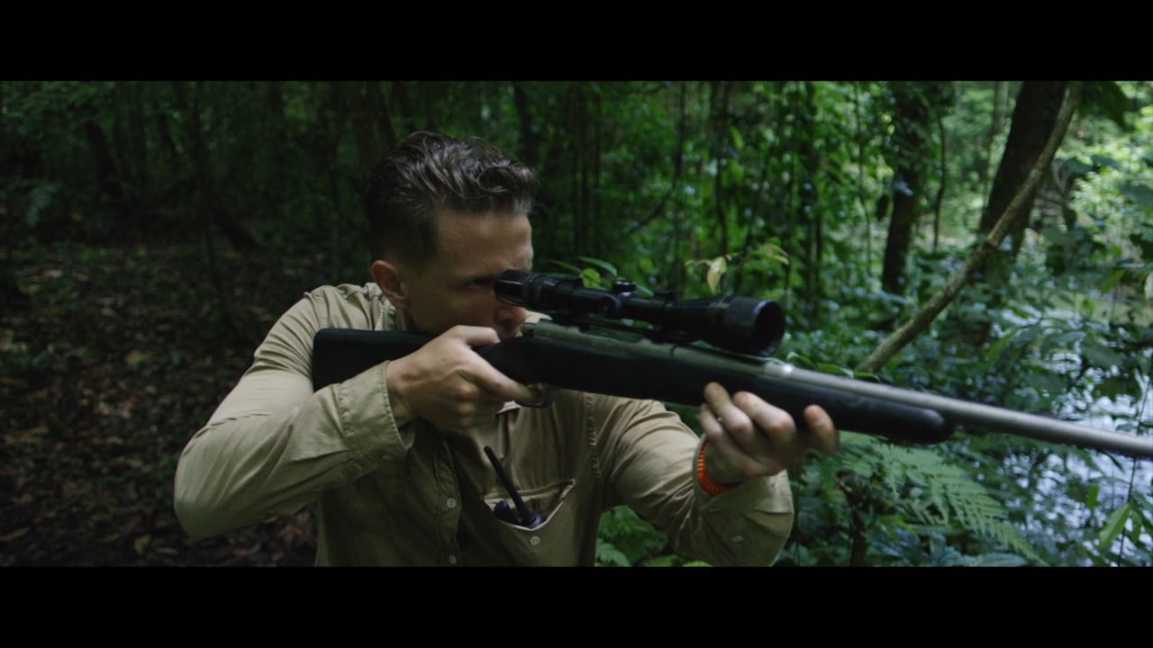 A man aiming a rifle in the Chiapas forest in Cachorro