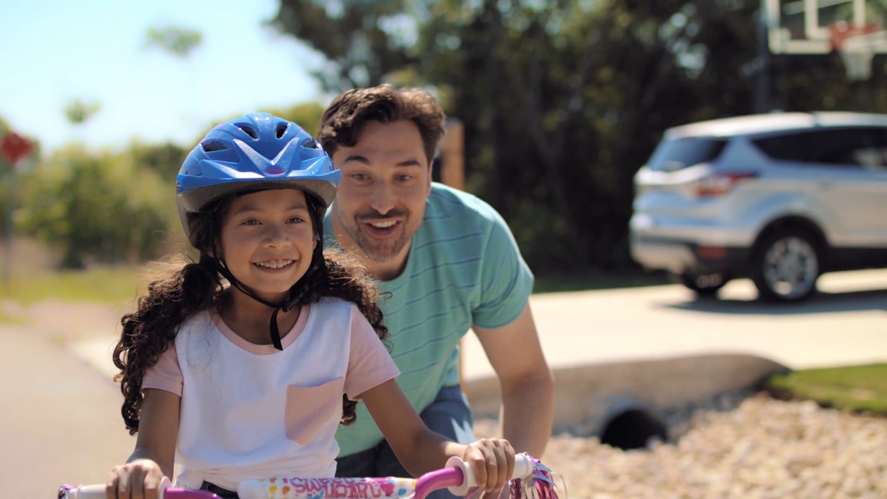 A father helping his daughter ride a bicycle