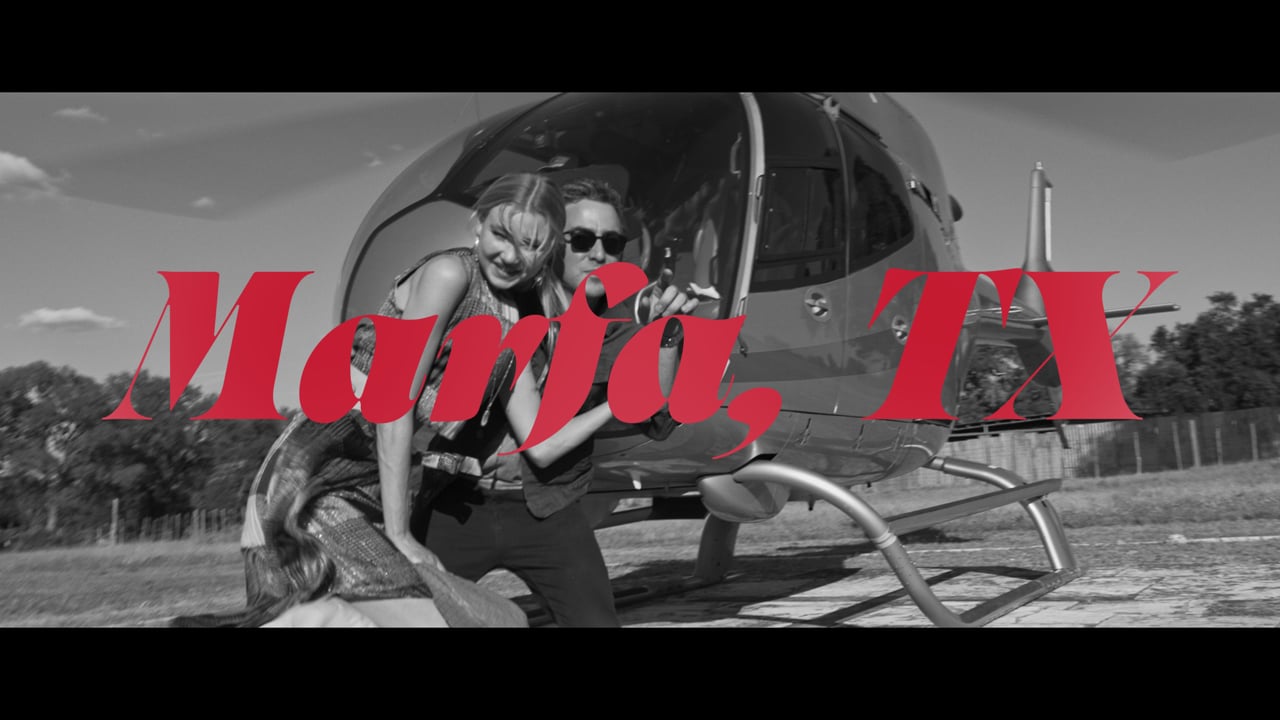 A couple beside a helicopter in the Marfa, TX. official trailer