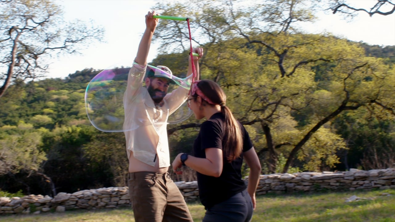 A performer creating a large bubble outdoors for Whole Earth Provisions